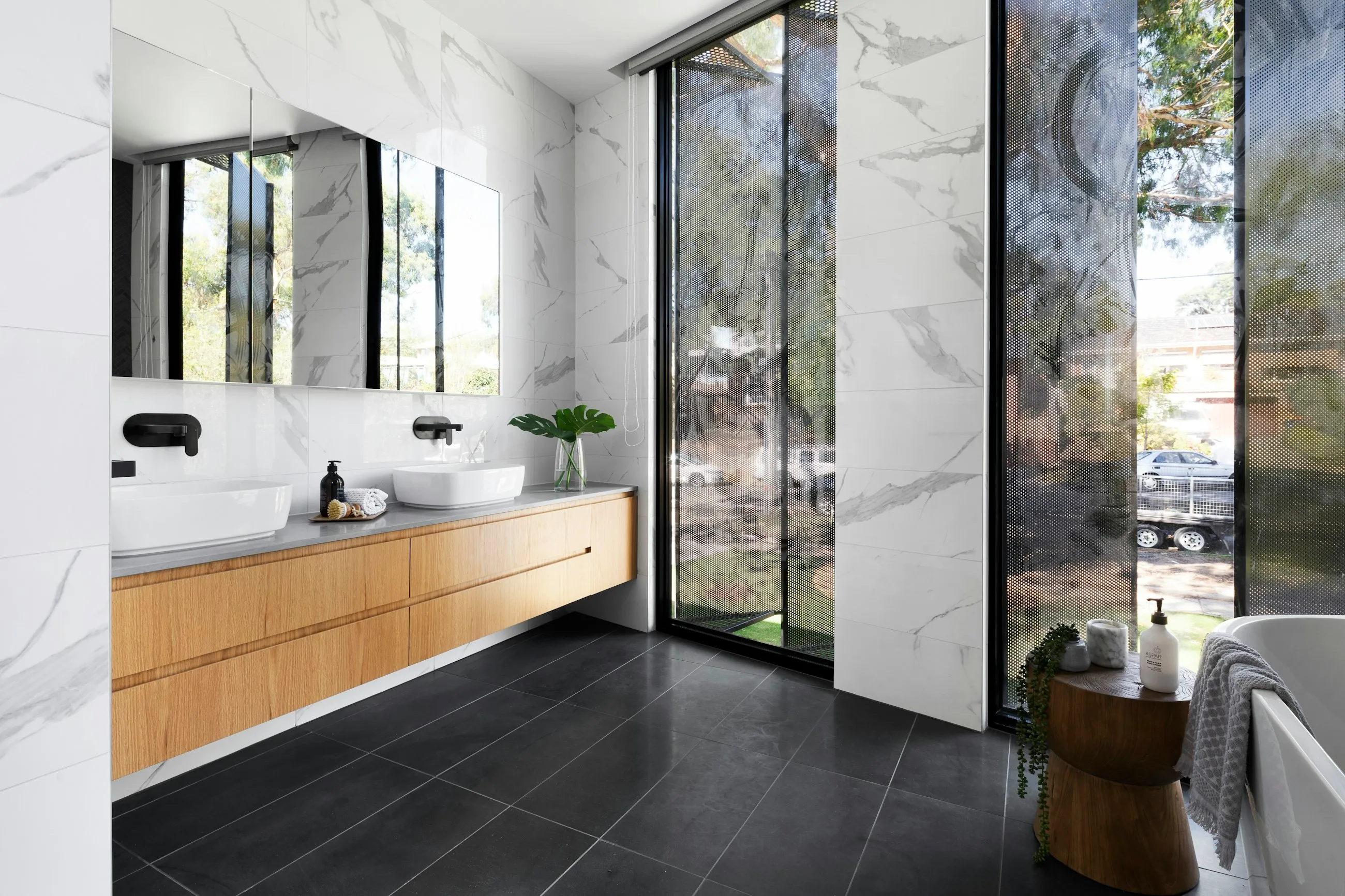 Baño revestido de mármol oscuro con lavabo de piedra
