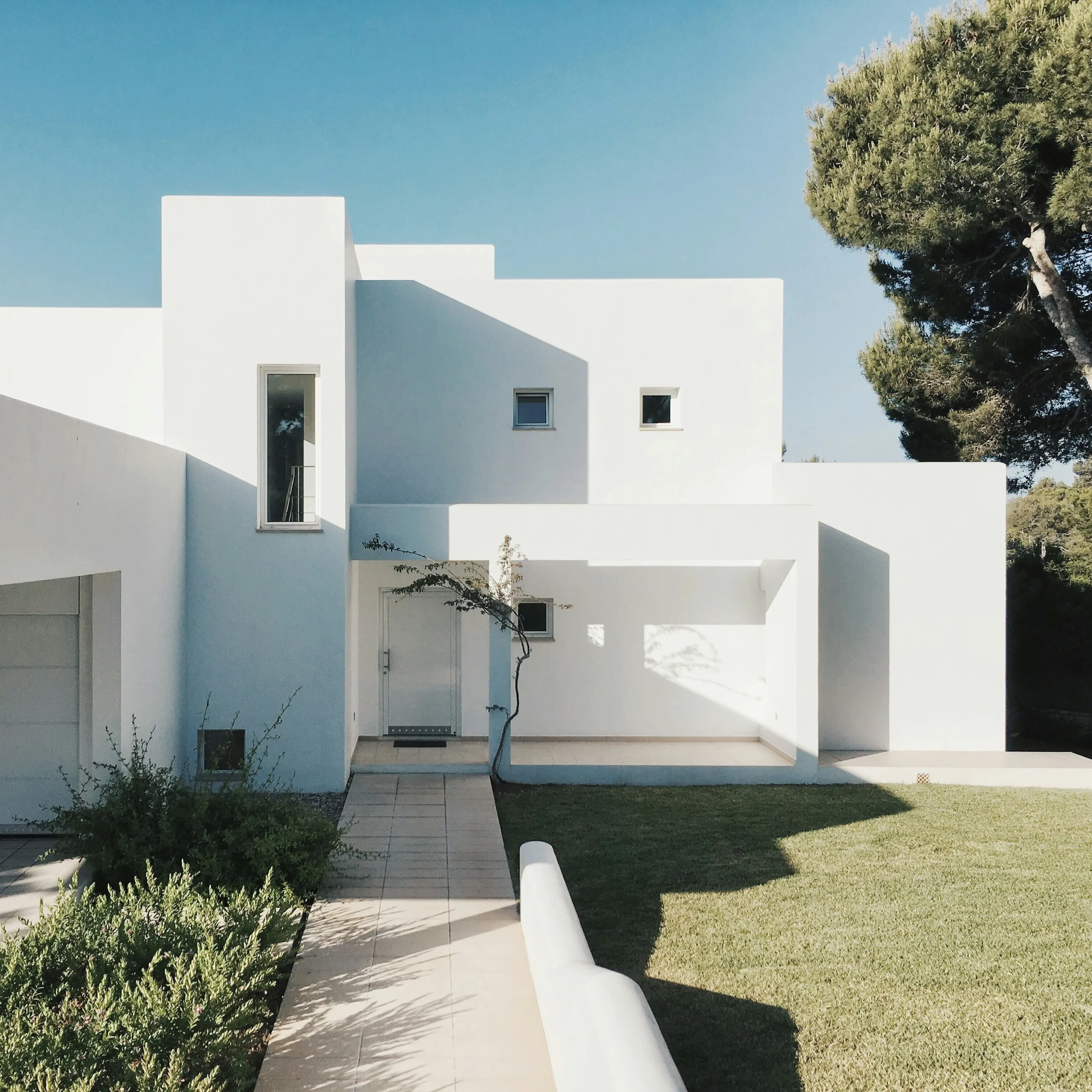 Fachada blanca de Casa Albufera entre árboles y luz de tarde
