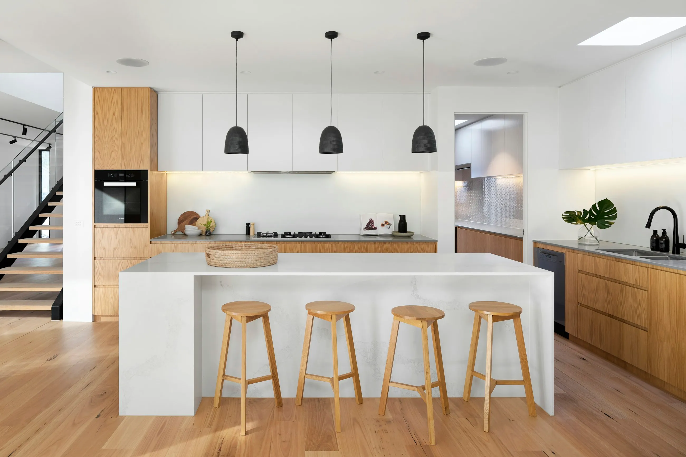 Cocina blanca con isla y taburetes de madera