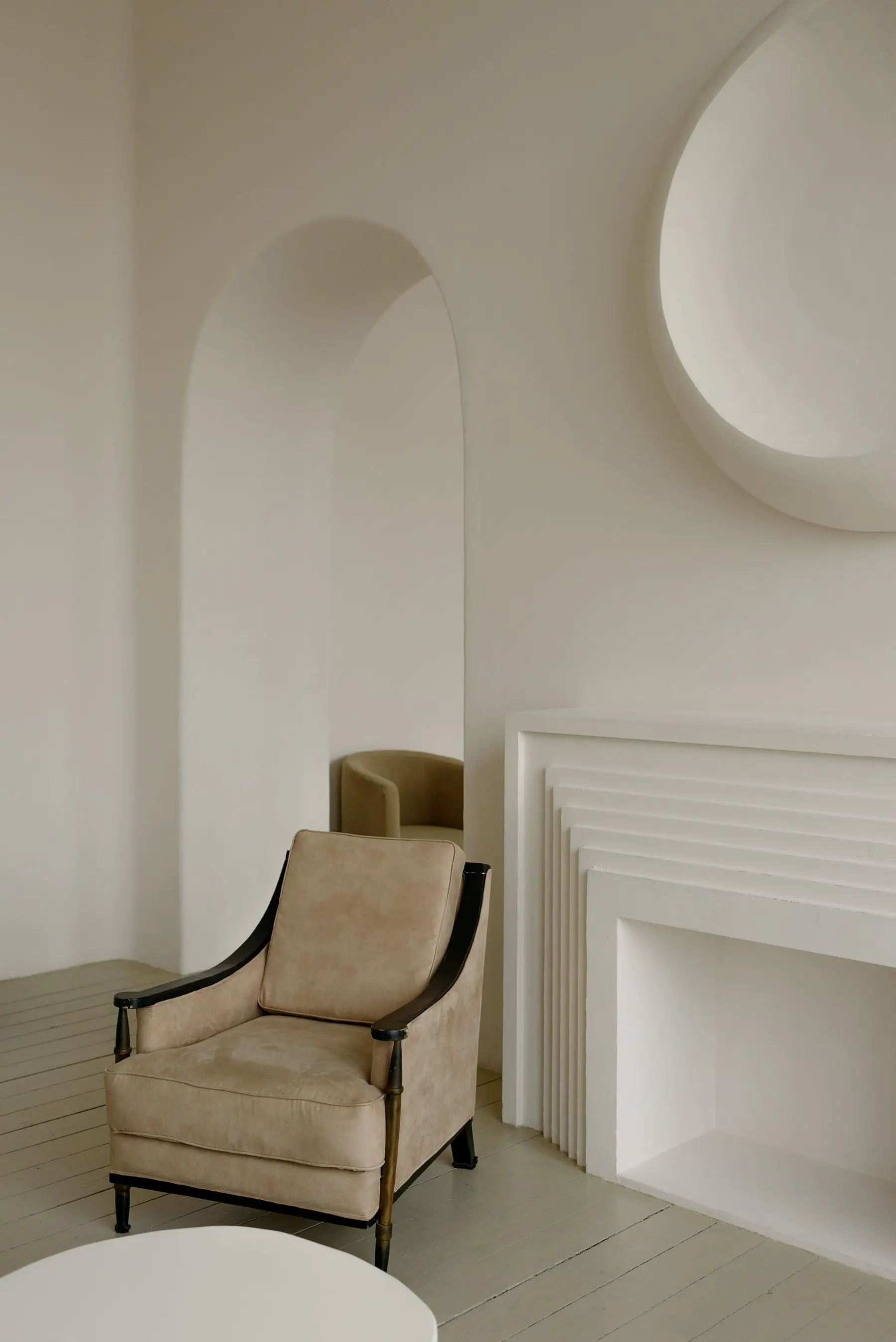 Sala de espera tranquila con paredes blancas, un arco y una butaca de piel