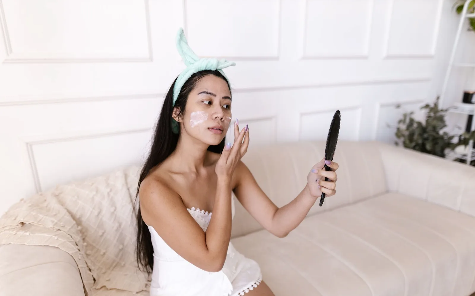 Mujer aplicando crema facial frente a un espejo