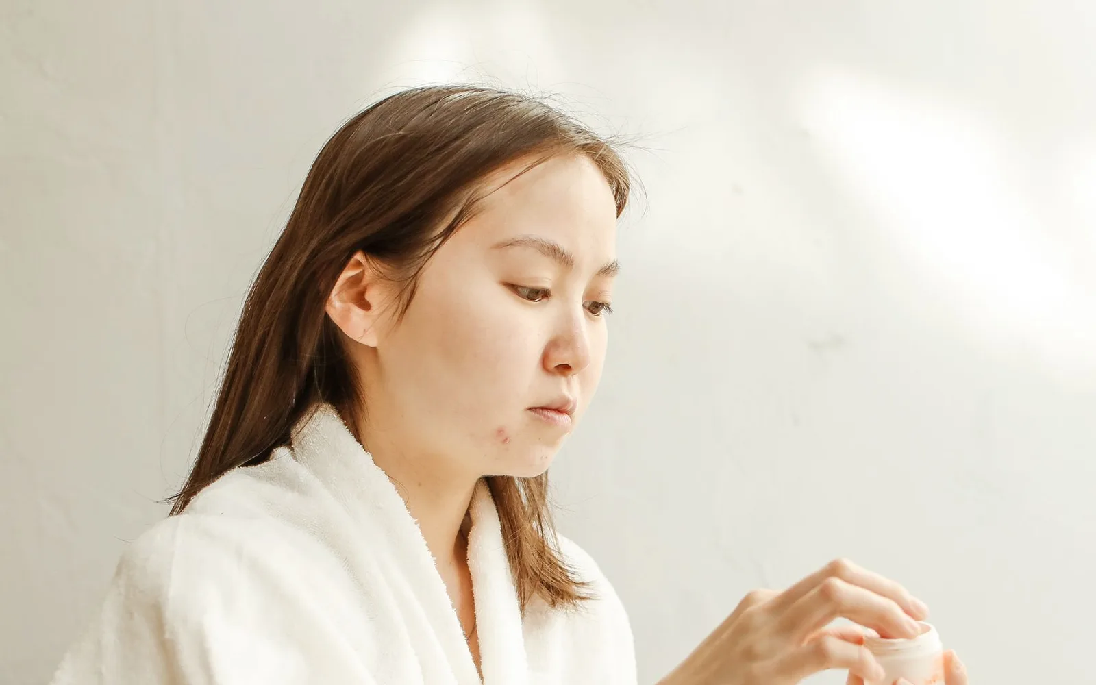 Mujer sosteniendo un producto de cuidado facial